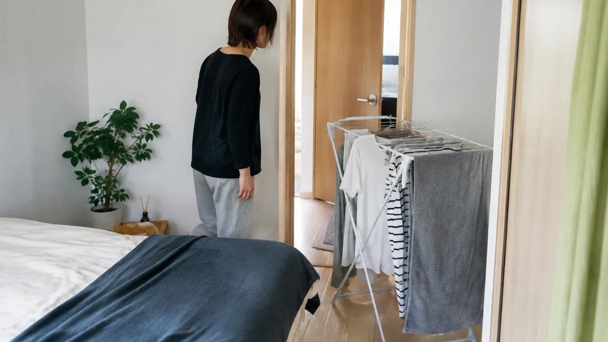 ベッドと扉の近くに物干しを置いた室内の通路