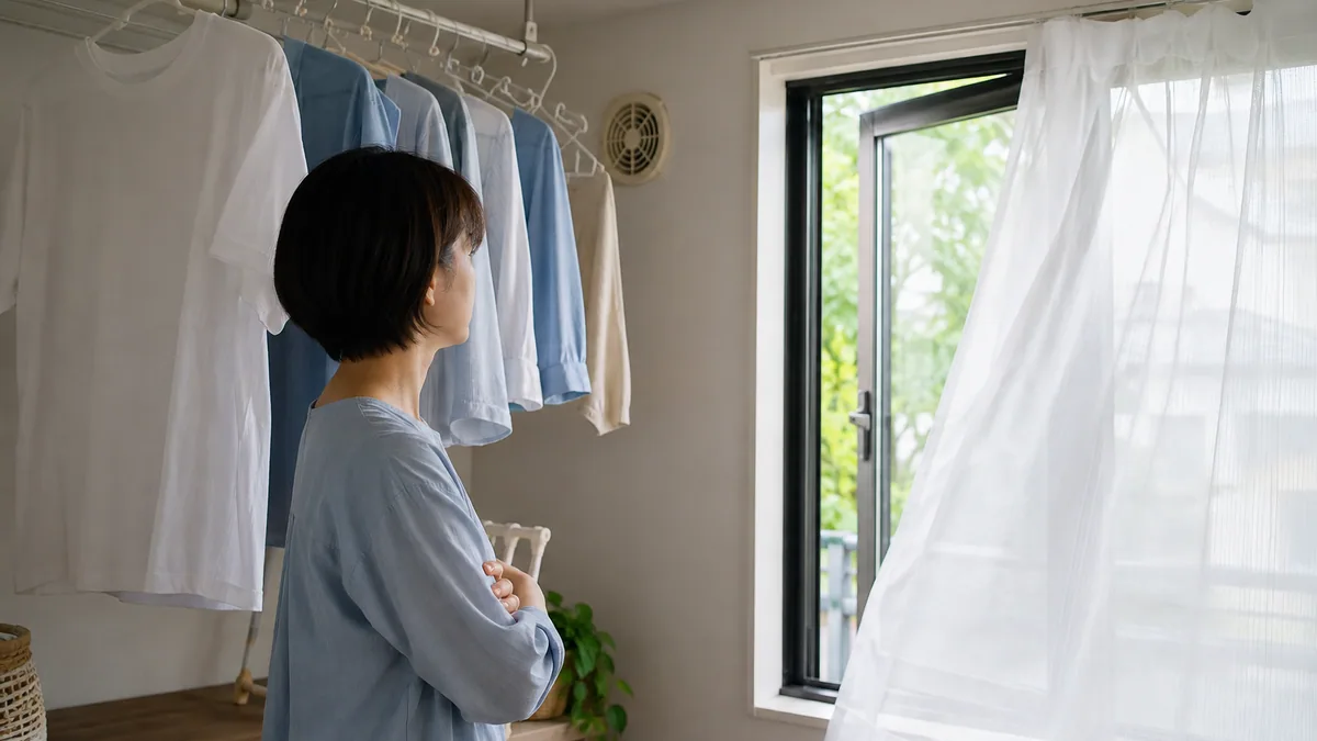 窓を少し開けた部屋で洗濯物を干している様子